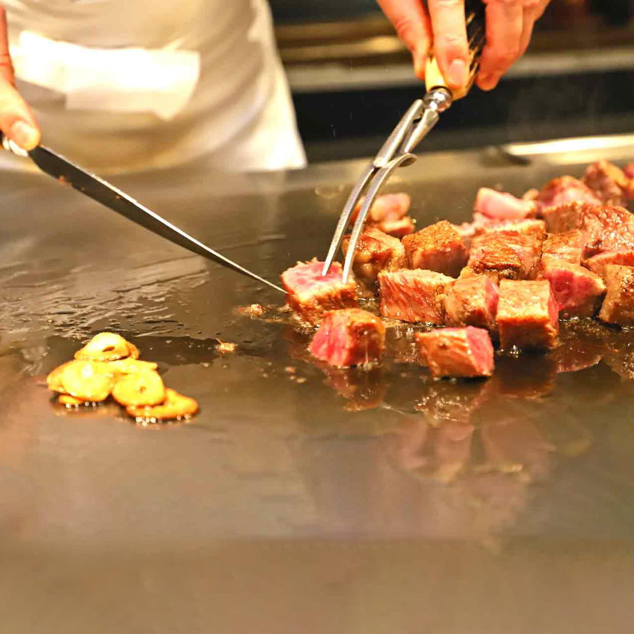 chef teppanyaki cuisinant de la viande